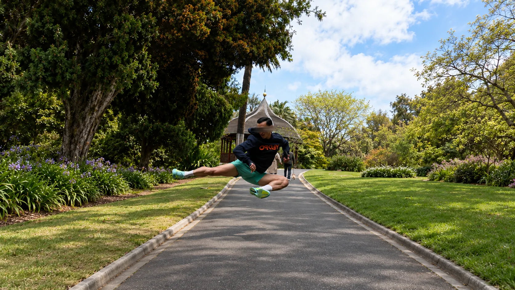 Me airborne above a path in a park, trees on both sides