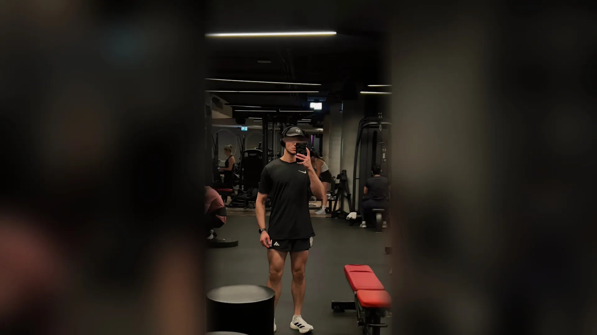 Me taking a mirror photograph in a gym, in dark training clothes