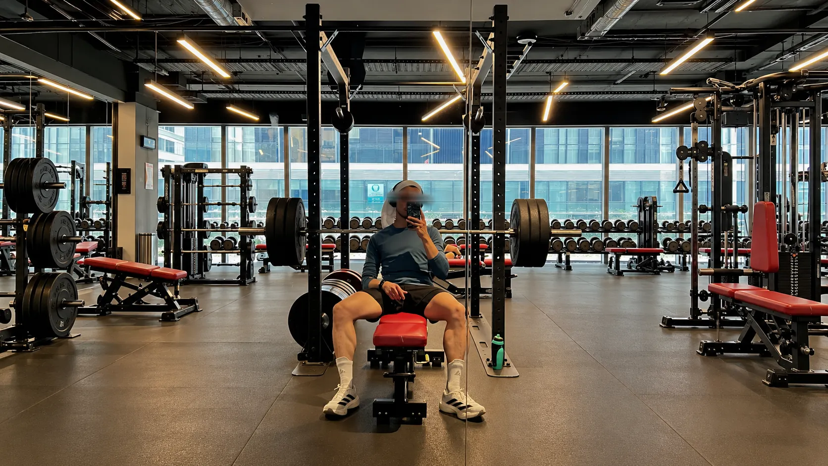Me seated by a loaded barbell and squat rack in a gym